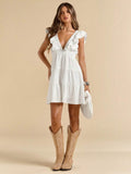 White mini dress with deep V neckline ruffle shoulder trim tiered skirt and tan cowboy boots