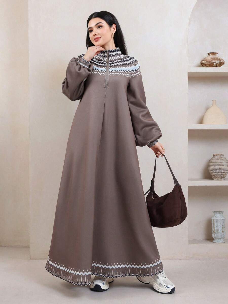 Front view of a model wearing a taupe ankle-length sweatshirt dress with geometric yoke, half zip and balloon sleeves
