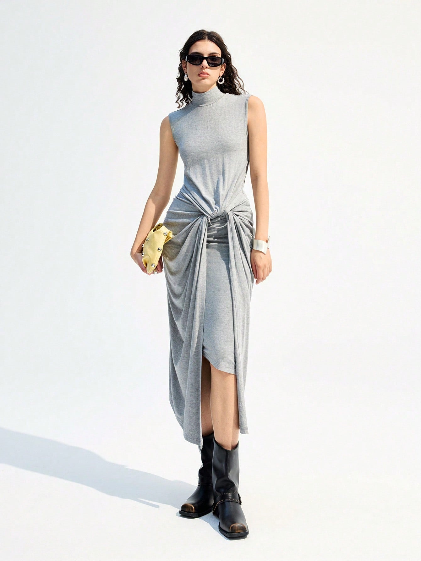 Turn heads with this playful sleeveless turtleneck dress, featuring a chic twisted waist and eye-catching metal ring detail. Its sleek grey hue adds a modern touch, while the long silhouette keeps things effortlessly elegant. Perfect for making a stylish statement wherever you go!