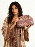 Model in boho dress holding pink patterned fabric clutch with rounded pouch shape