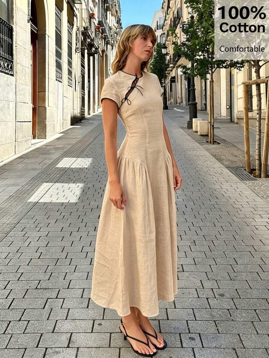 Street front view of apricot cotton retro maxi dress with short sleeves, black piping, and lace-up neckline