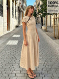 Street front view of apricot cotton retro maxi dress with short sleeves, black piping, and lace-up neckline