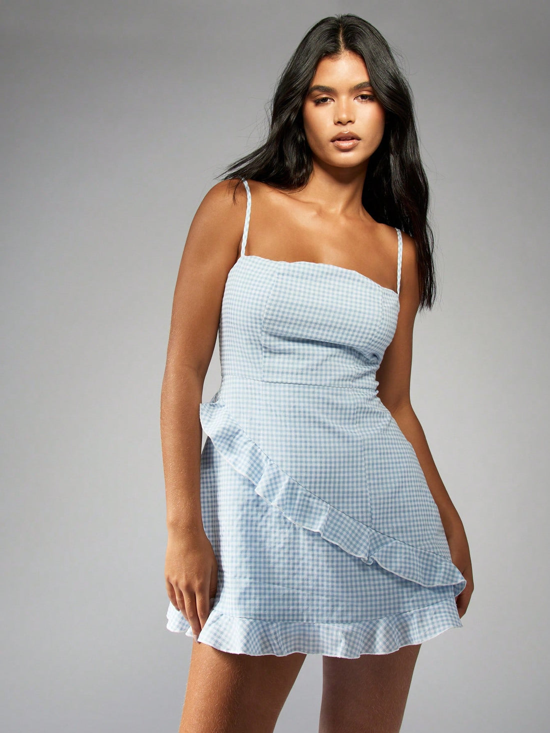 Get ready for stylish outings with our Trendy Checked Print Strappy Ruffle Detail Cami Mini Dress! This dress features a trendy checkered print and flirty ruffle details, perfect for making a statement. The strappy design adds a touch of edginess to this must-have piece.