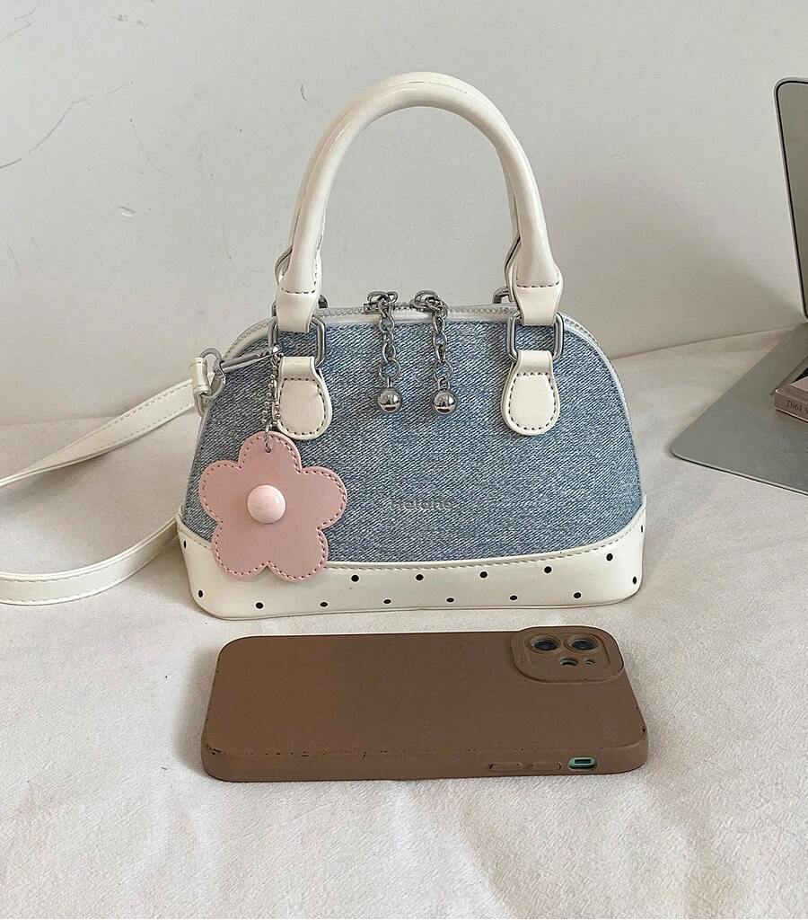 Front view of baby blue dome handbag with cream handles, dotted trim and pink flower charm beside a phone