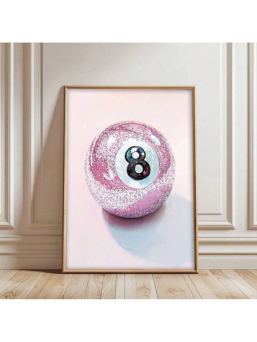 Pink glitter 8-ball canvas poster in a gold frame leaning against a beige paneled wall