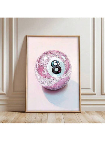 Pink glitter 8-ball canvas poster in a gold frame leaning against a beige paneled wall