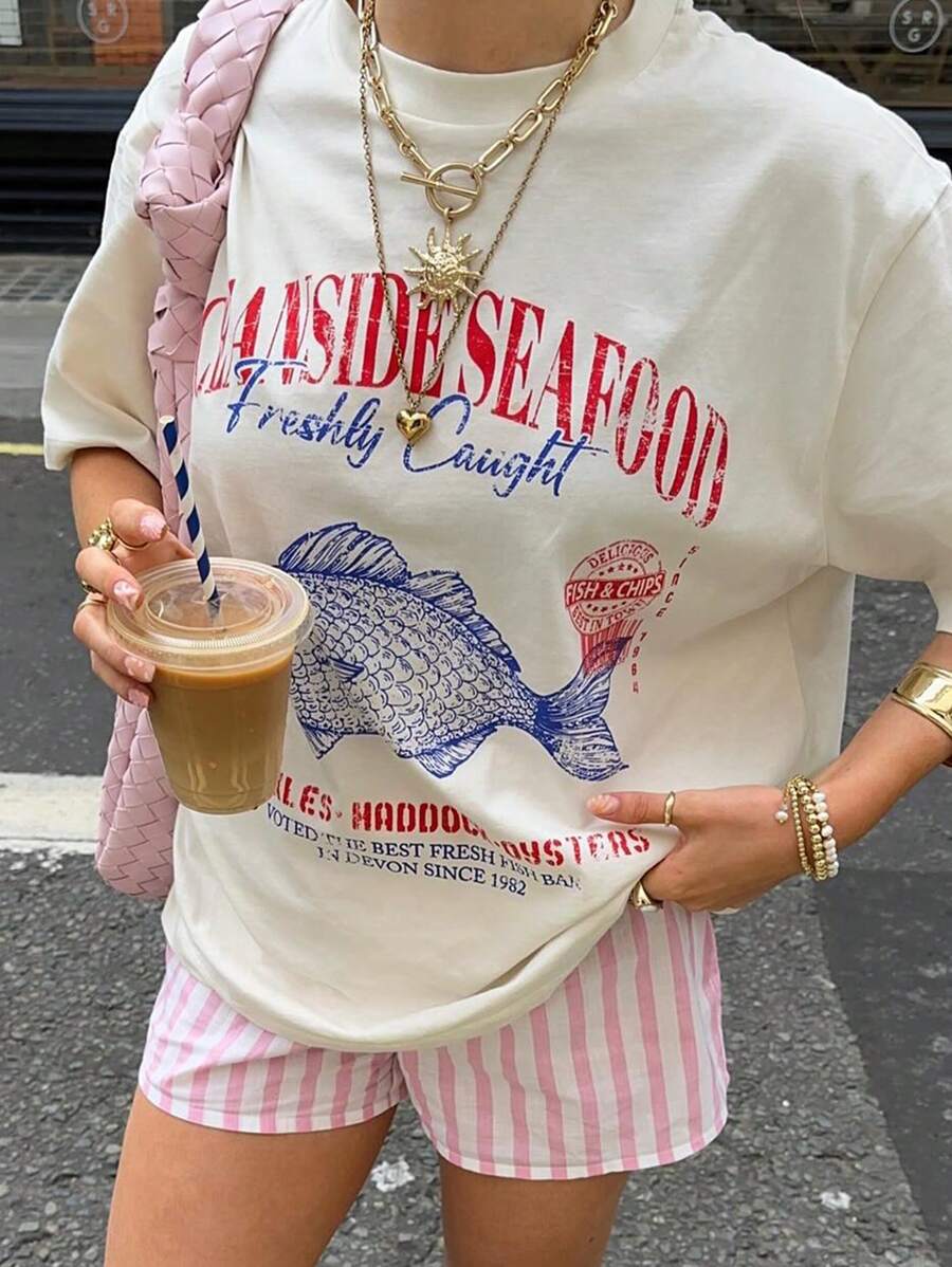Close front view of white oversized Seaside Seafood graphic tee with red blue fish slogan print