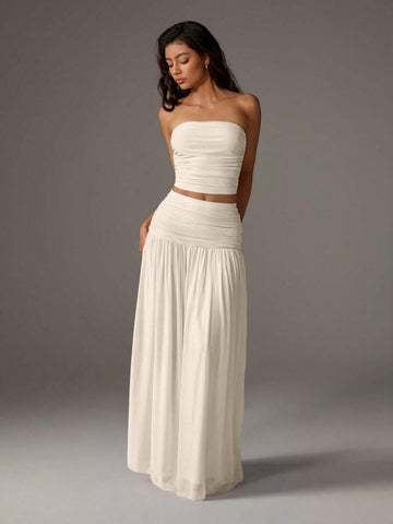 Elevate your style with this chic two-piece set featuring a cropped mesh bustier paired with a flowing maxi skirt. The solid color design offers versatile elegance, while the sheer mesh bustier adds modern sophistication. 
