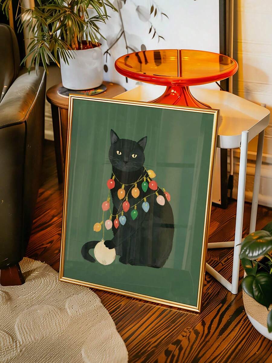 Portrait view of black cat Christmas canvas print in gold frame beside a houseplant