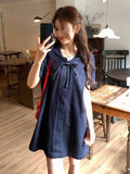 Three-quarter front view of dark-indigo sailor-collar denim mini dress with chest bow and short sleeves