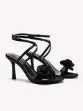 Black high-heeled sandals with floral details on a white background
