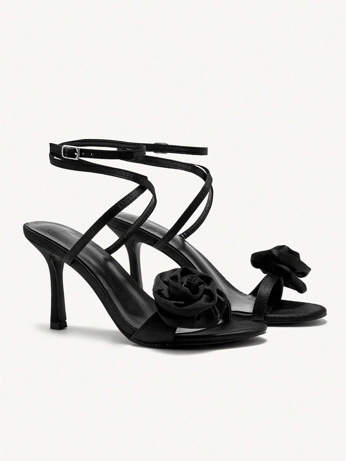 Black high-heeled sandals with floral details on a white background