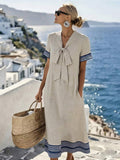 Front three quarter view of apricot tie front midi dress with blue border trim and pockets