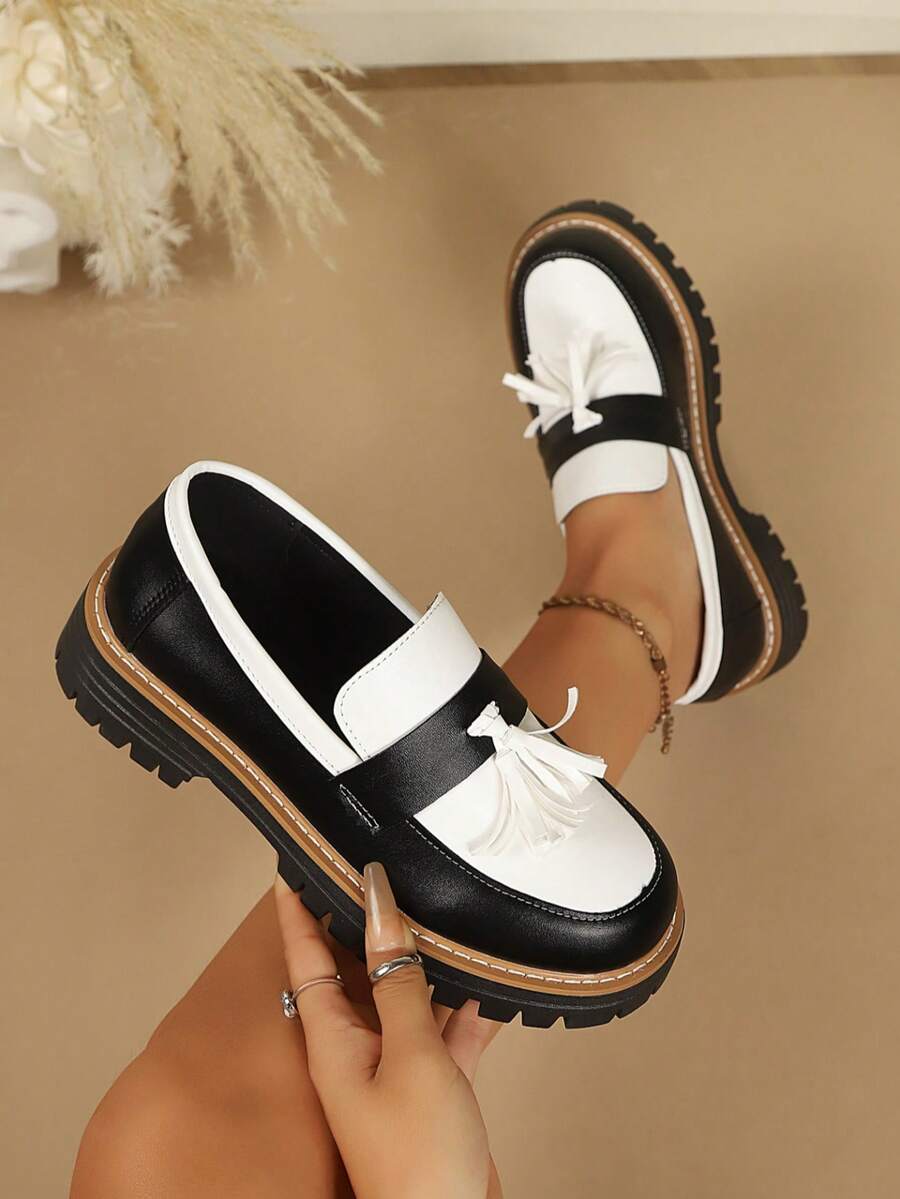 Top-side view of black and white tassel loafer with rounded toe, brown welt, and thick lug sole