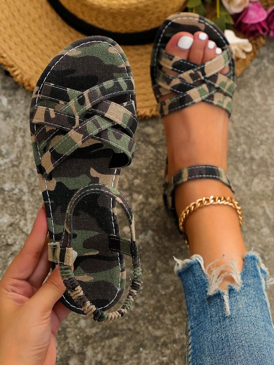 Top handheld view of camouflage interwoven flat sandals with one sandal worn outdoors