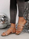 Gold crystal embellished flat slide sandals with rhinestone straps and black outsole
