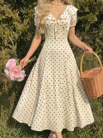 Front outdoor view of cream polka dot ruffle collar dress with puff sleeves and tie bust