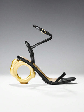 Black and gold ankle strap sandals with circular sculptural heel in studio