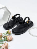 Front three-quarter view of black toe-post platform sandals with gold buckles