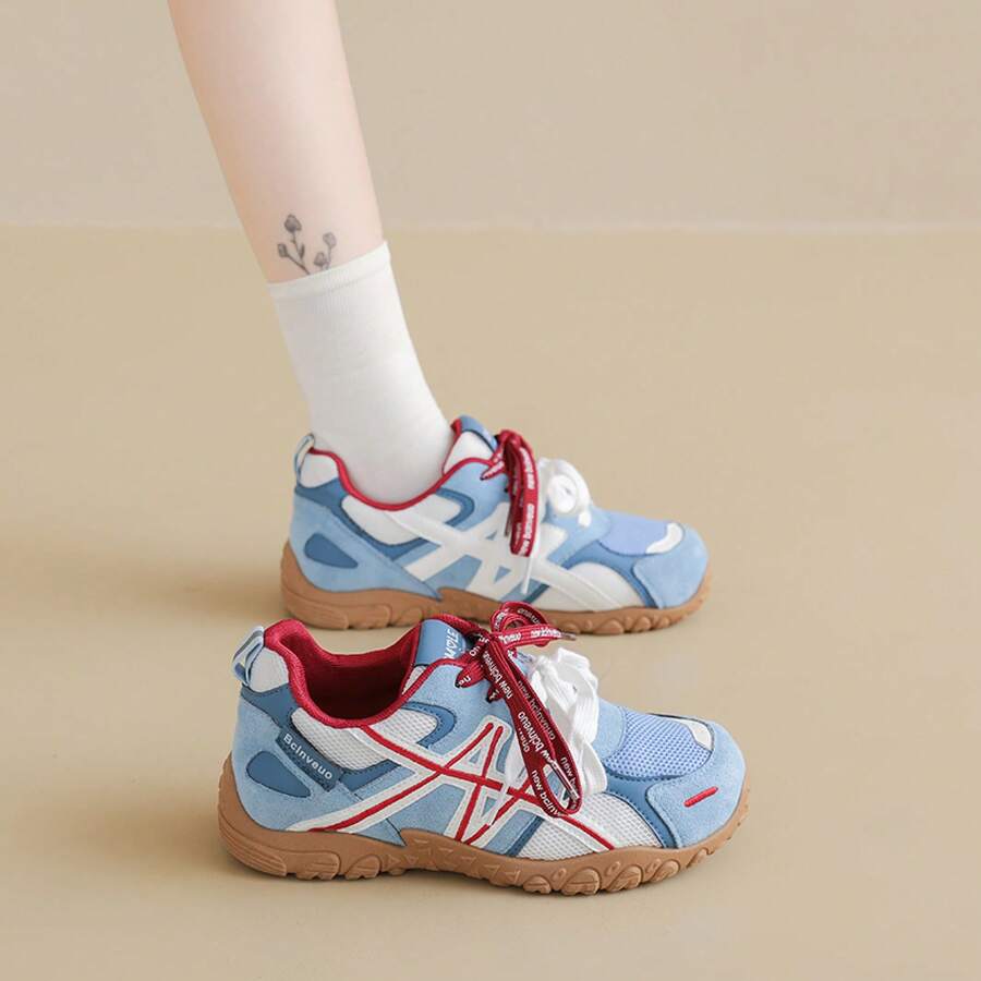 Side view of light blue, white, and red colorblock sneaker with white laces and gum tread sole