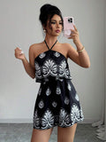 Mirror front view of black printed halter romper with layered ruffle bodice and gathered waist
