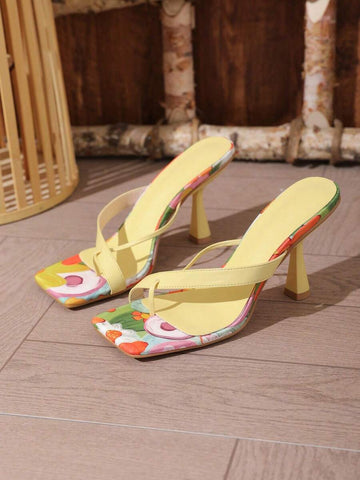 Three-quarter product view of yellow square-toe high heel thong sandals with colorful printed footbeds