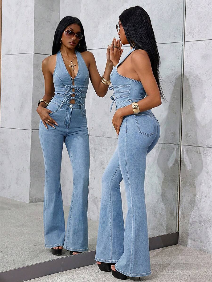 Full-length side view of a light-wash halter denim jumpsuit with flared legs and bow-front cutouts reflected in a mirror