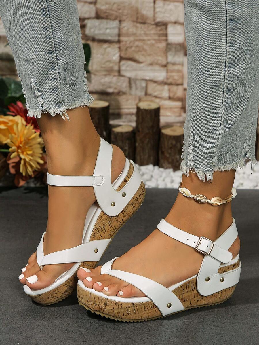 Three-quarter on-foot view of white studded wedge platform sandals with cropped denim