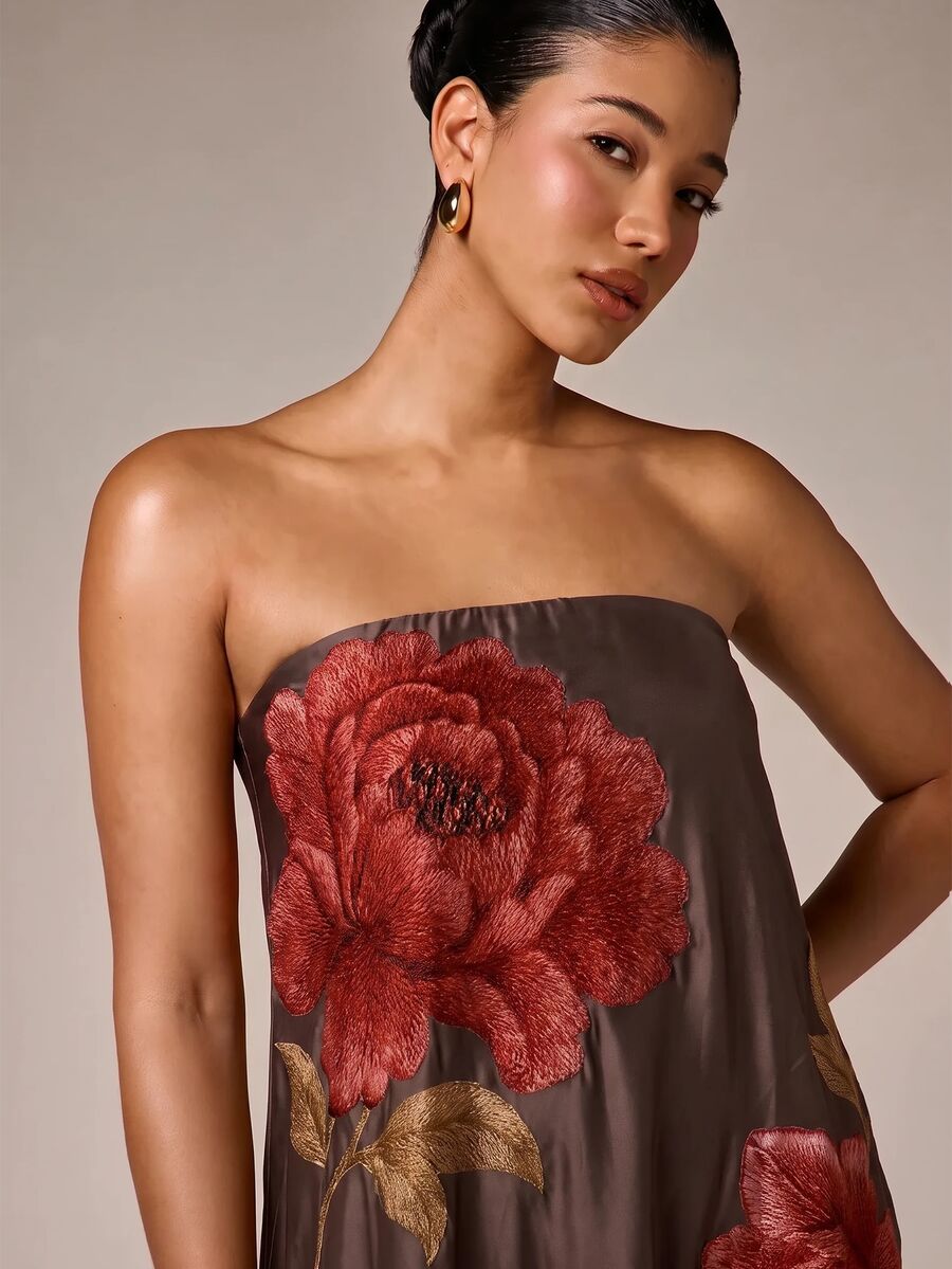 Close view of brown satin bodice with large red rose embroidery at strapless neckline