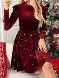 Close-up of burgundy velvet dress with pearl embellishments, round neckline, and ruffled shoulders