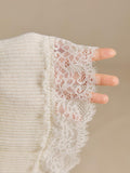 Close-up of the ivory rib-knit sleeve ending in floral openwork lace cuff trim