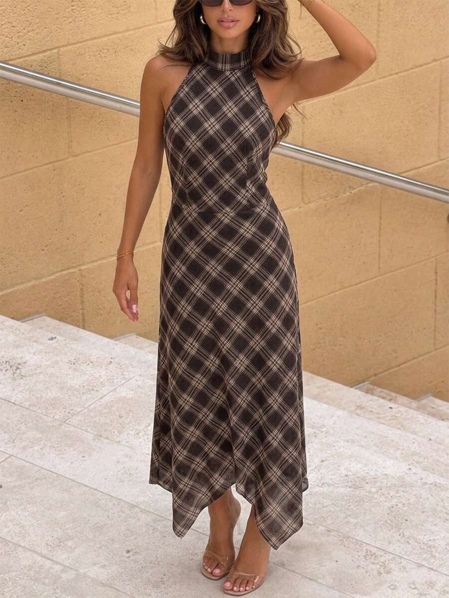 Front view of a brown and cream plaid halter dress with a fitted bodice and pointed asymmetric hem on stone steps.