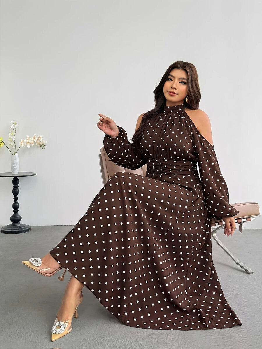 Seated front view of brown polka-dot flared halter maxi dress