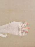 Close-up of ivory knit sleeve finished with a wide floral lace cuff