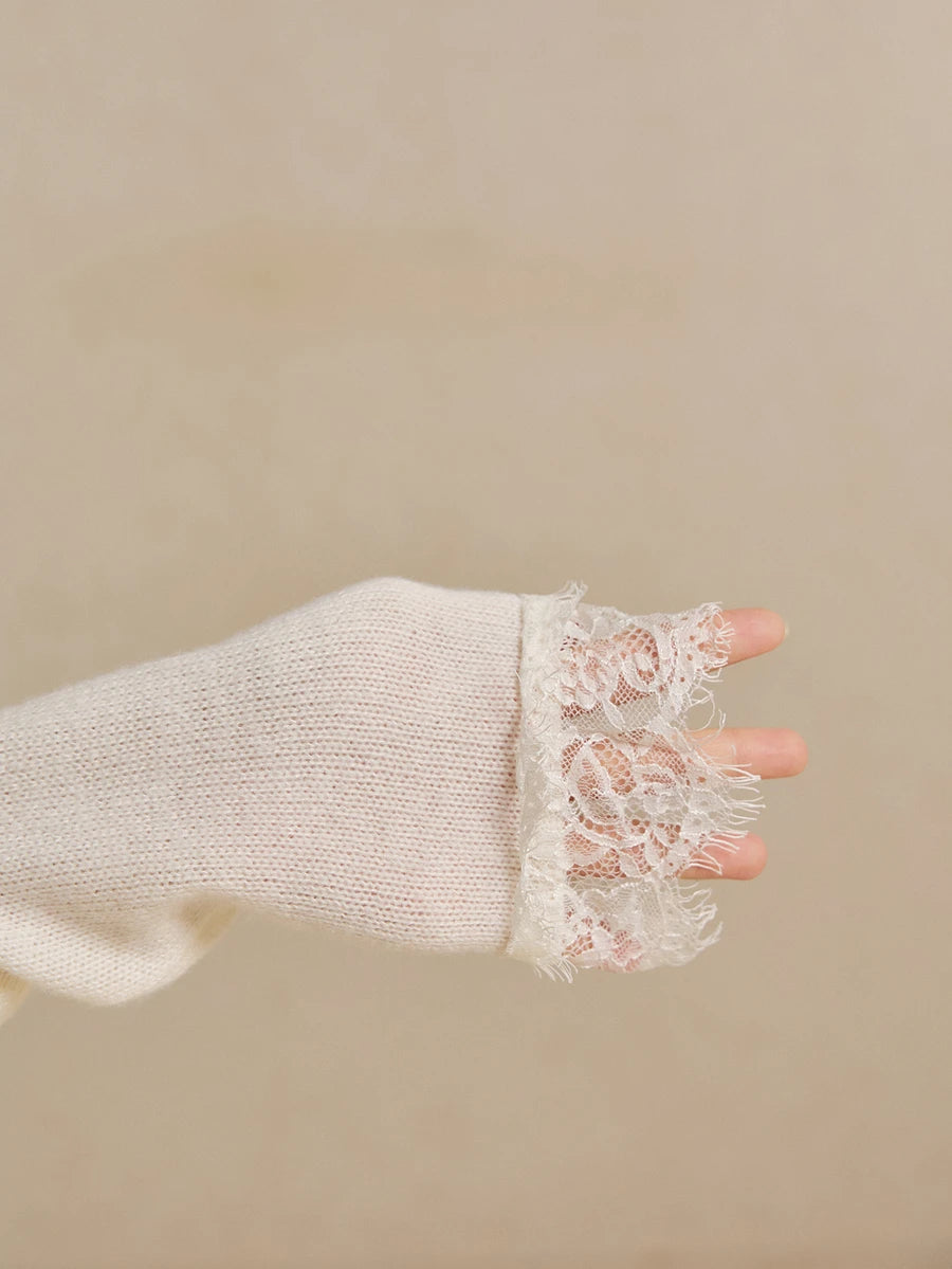 Close-up of ivory knit sleeve finished with a wide floral lace cuff