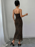 A woman viewed from behind wearing a leopard-print spaghetti-strap maxi dress with a fitted bodice and flared hem, paired with black mule heels in an indoor room with a light gray wall and floor.