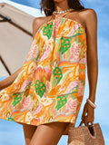 Front close-up of orange green tropical floral mini dress at the beach