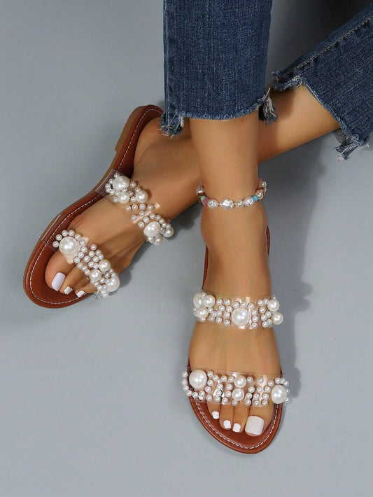 These elegant Clear Strap Flat Sandals are adorned with delicate imitation pearls, adding a touch of sophistication to any outfit. The clear straps provide a modern and sleek look, while the flat design offers comfort and practicality. Perfect for any stylish lady looking to elevate her wardrobe.