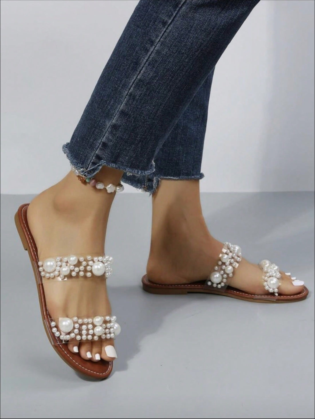 These elegant Clear Strap Flat Sandals are adorned with delicate imitation pearls, adding a touch of sophistication to any outfit. The clear straps provide a modern and sleek look, while the flat design offers comfort and practicality. Perfect for any stylish lady looking to elevate her wardrobe.