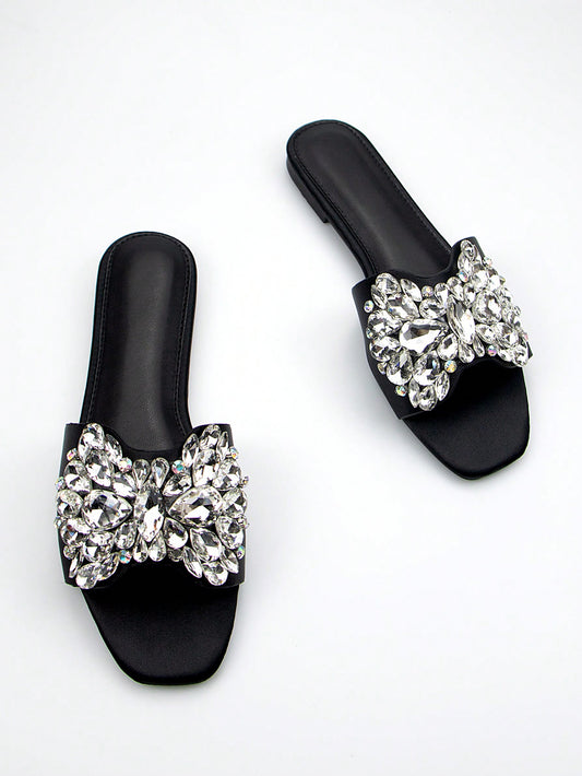 Add a touch of elegance to any party outfit with our Sparkling Elegance Flat Sandals. Designed with a square-toed silhouette and adorned with rhinestones, these black suede sandals are sure to make you stand out. Perfect for adding a touch of sparkle and style to your ensemble.