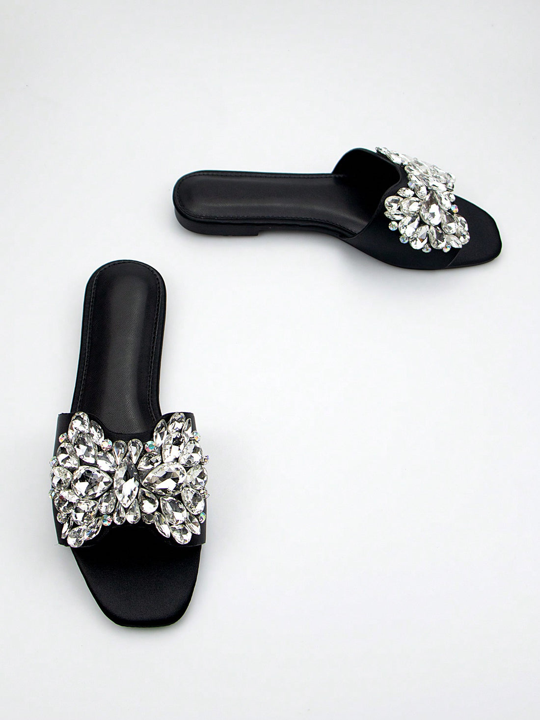 Add a touch of elegance to any party outfit with our Sparkling Elegance Flat Sandals. Designed with a square-toed silhouette and adorned with rhinestones, these black suede sandals are sure to make you stand out. Perfect for adding a touch of sparkle and style to your ensemble.