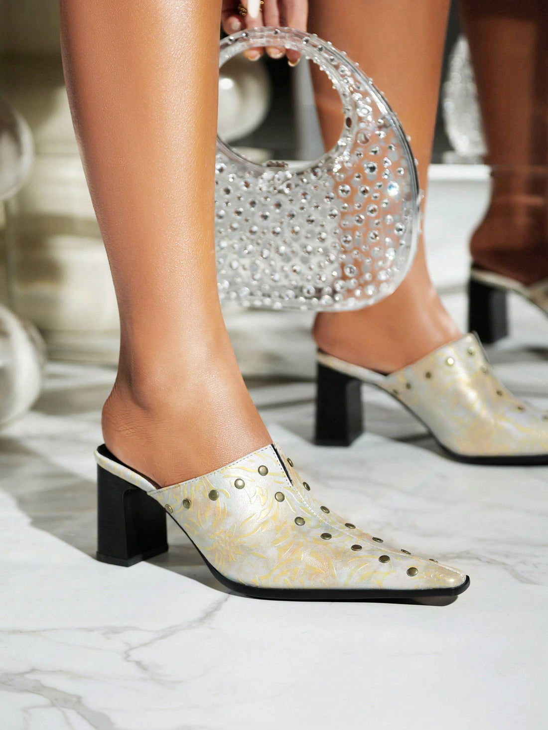 Introducing our stylish studded high-heeled mules for women. These chunky-heeled slippers add a touch of glamour to any outfit. With a comfortable <a href="https://canaryhouze.com/collections/women-canvas-shoes" target="_blank" rel="noopener">slip-on</a> design and durable construction, you can confidently elevate your look with these mules. Perfect for any occasion.